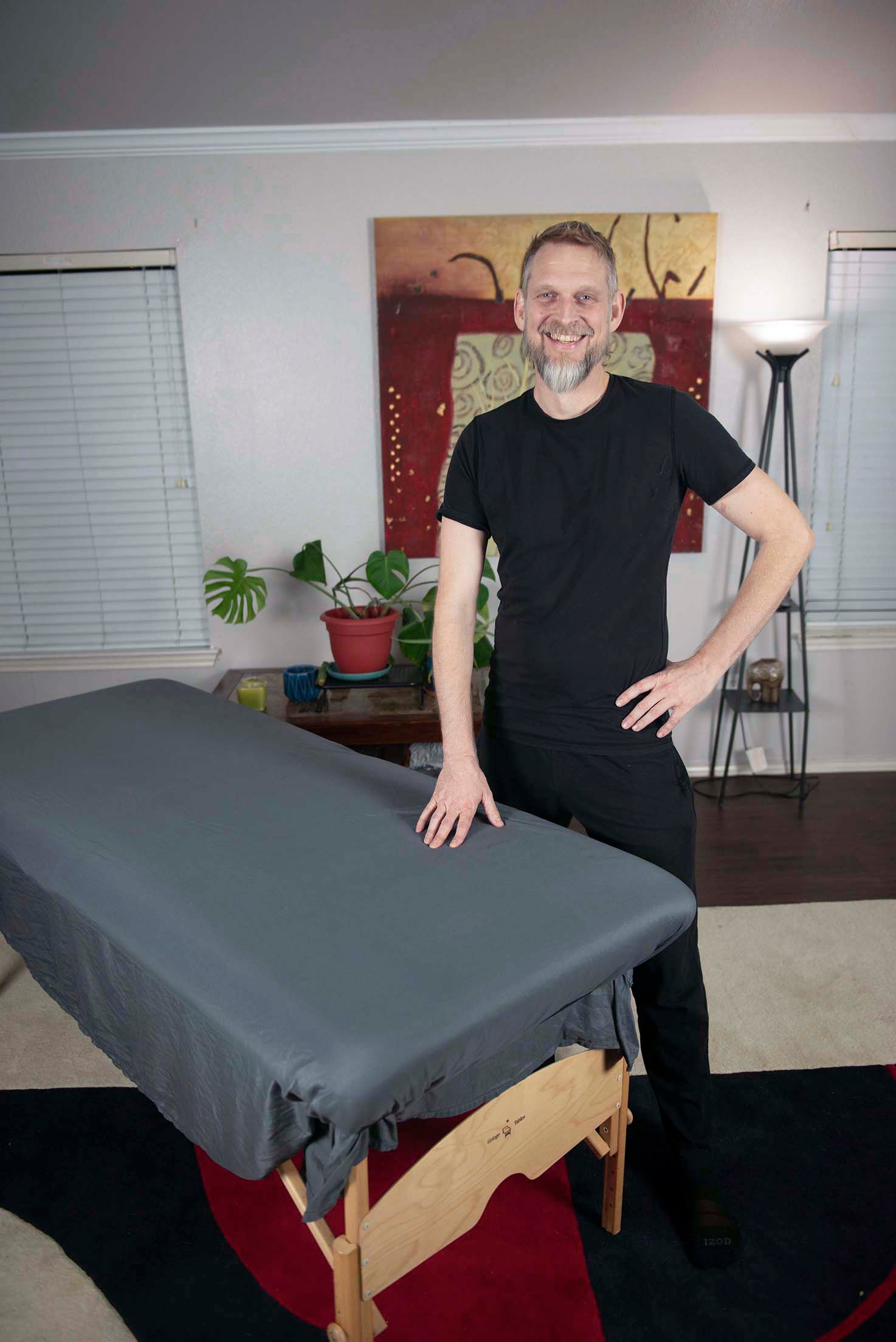 Daniel Brigham, board certified Structural Integrator, in the Austin studio beside the treatment table